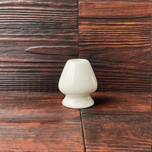 Keramischer Chasen Yasume Halter für Matcha-Besen auf dunklem Holztisch. Produkt aus dem iūgen Shop.