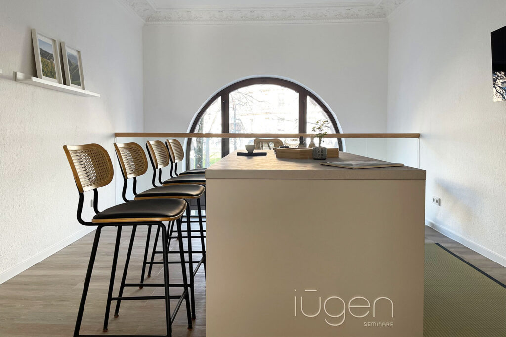 Heller Raum mit Hochtisch, Barhockern und großem Rundbogenfenster für Tee-Seminare bei iūgen.