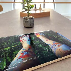 Poster mit farbig bemalten Beinen und Zitat „Be a voice, not an echo“ auf einem Tisch in heller Seminarumgebung.