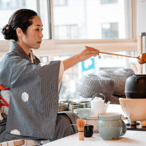 Einblick in eine Tee-Zeremonie. Person im traditionellen Kimono gießt während einer japanischen Teezeremonie Wasser aus einer Kelle in einen Teekessel.